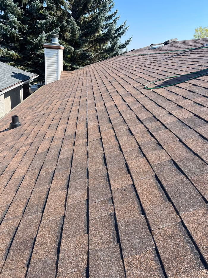 Brown shingle roof overview with chimney ridge view