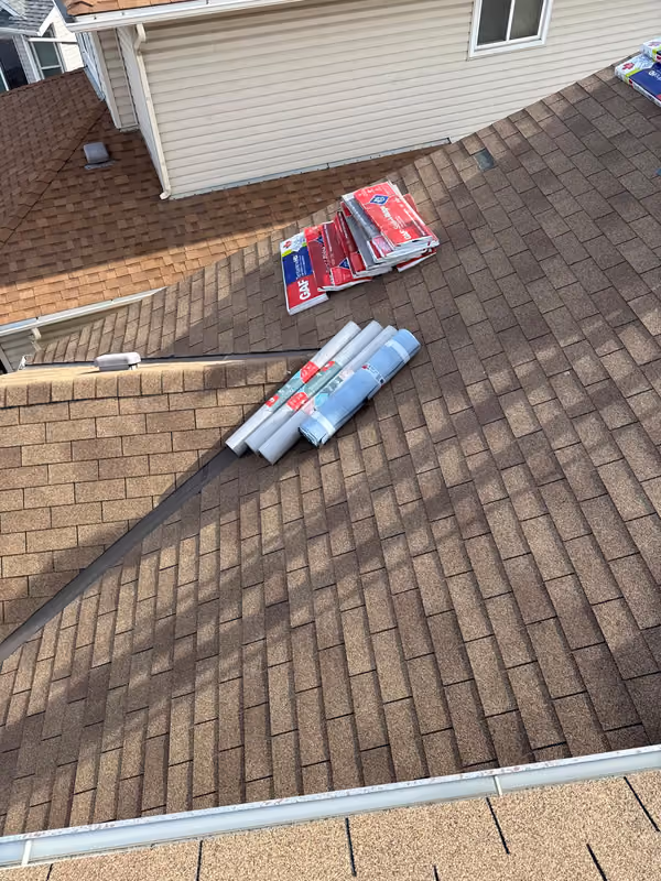 Caulking tubes and supplies staged on finished shingles