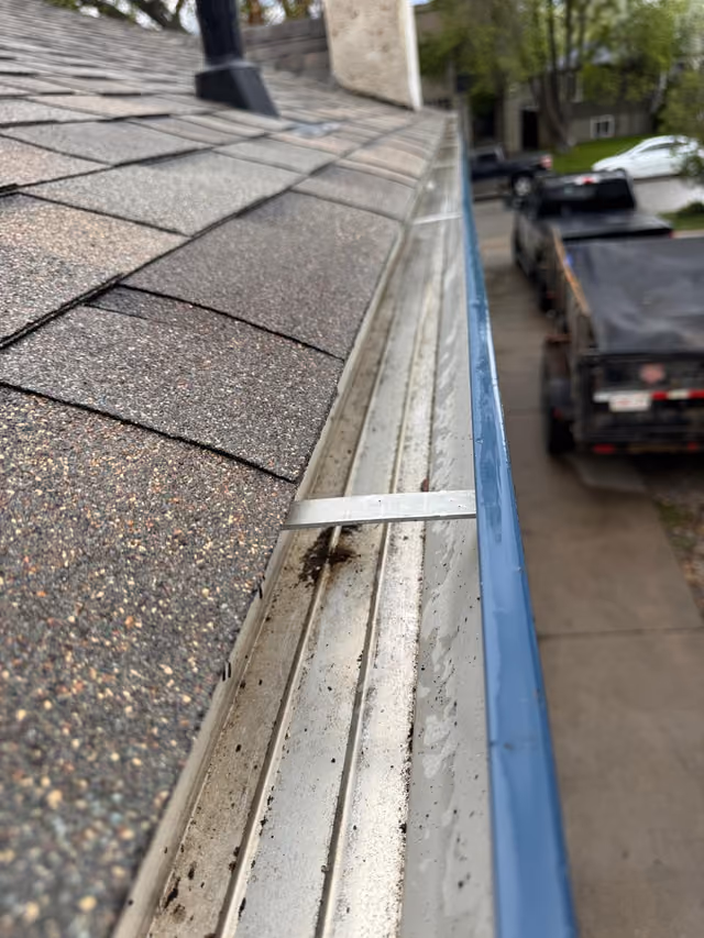 Close up debris in eavestrough along shingle edge