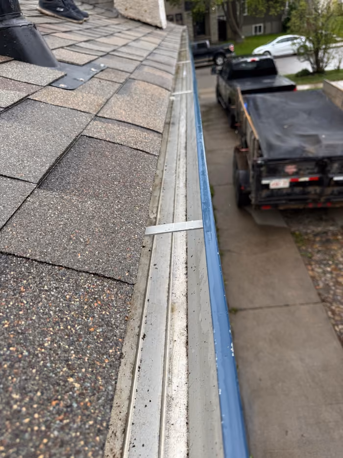 Close up eavestrough along shingle edge from roof