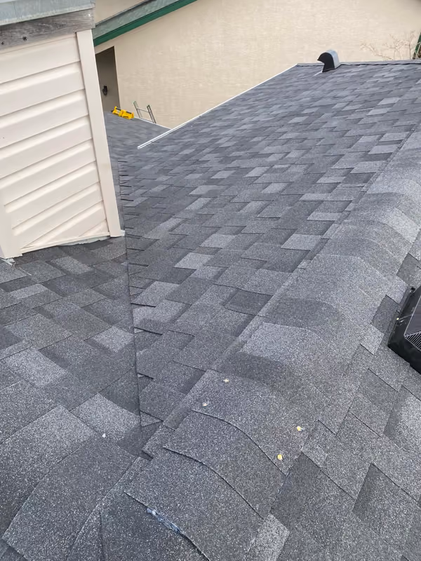 Finished charcoal shingles beside vinyl siding wall