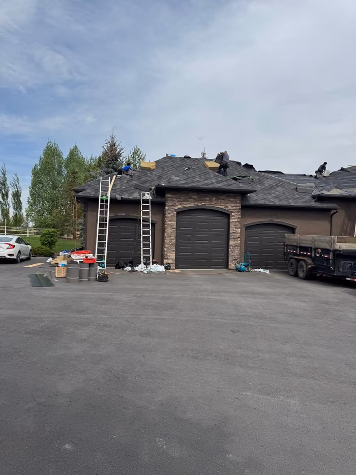Ladders against house crew working on roof above garage