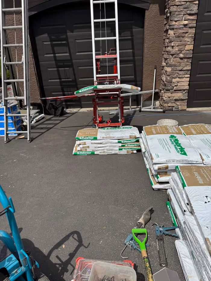 Ladders shingle cutter and tools staged in driveway