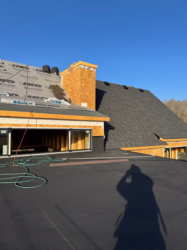Low slope membrane deck beside new shingled roof