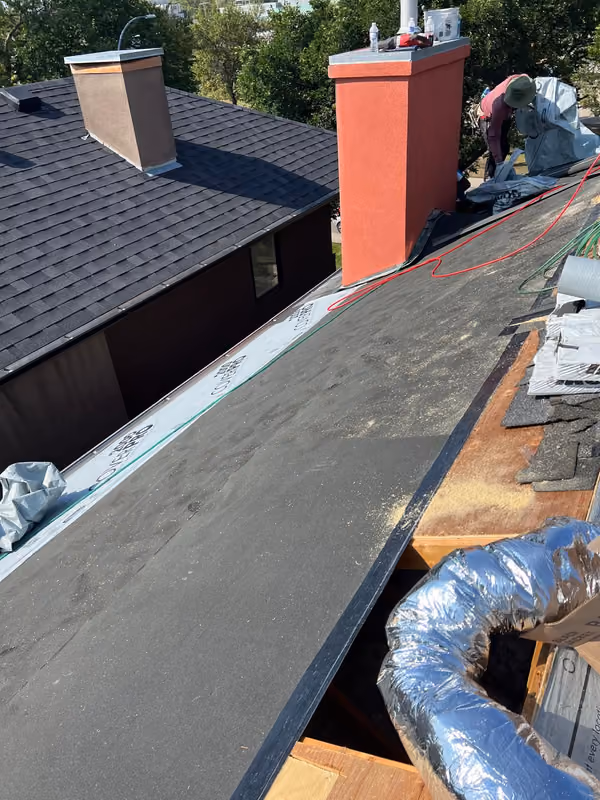 Low slope section with black membrane beside stucco chimney