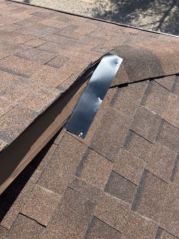 New metal flashing set into brown shingle valley