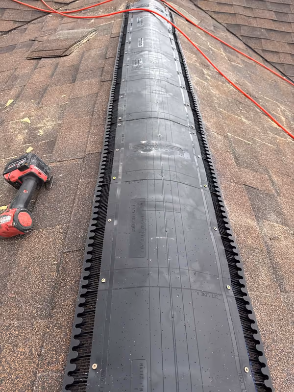 Ridge vent installed along shingle ridge with tools
