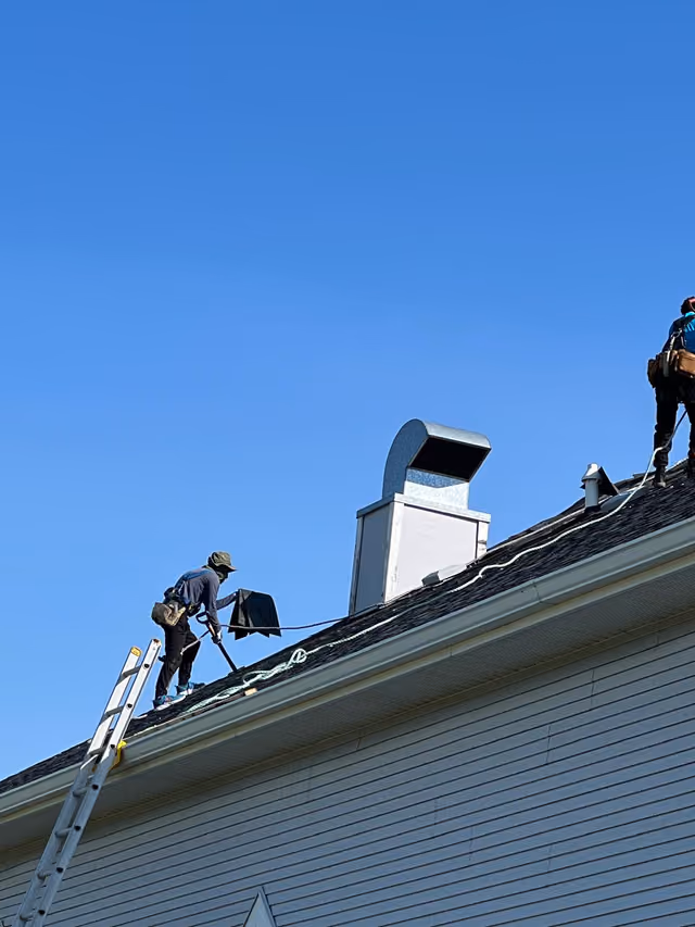 Roofer climbing ladder to ridge tear off underway