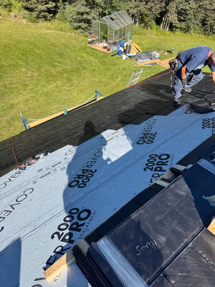 Roofer installing synthetic slate shingles over underlayment
