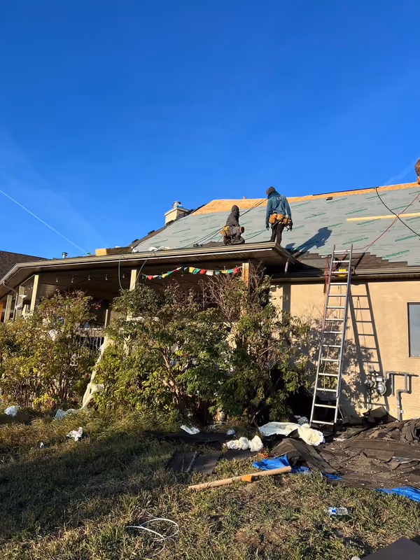 Roofers and ladders at eave ground level view