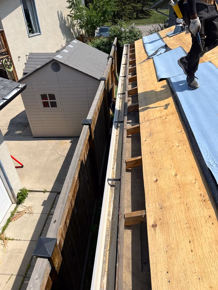 Worker installing ice water membrane at open eave